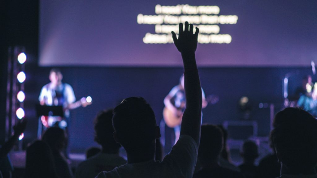 Picture of someone raising their hand in a church service.