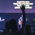 Picture of someone raising their hand in a church service.