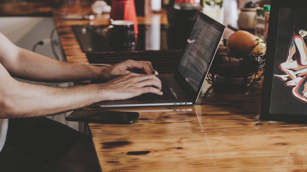 Person typing on a computer in a coffee shop